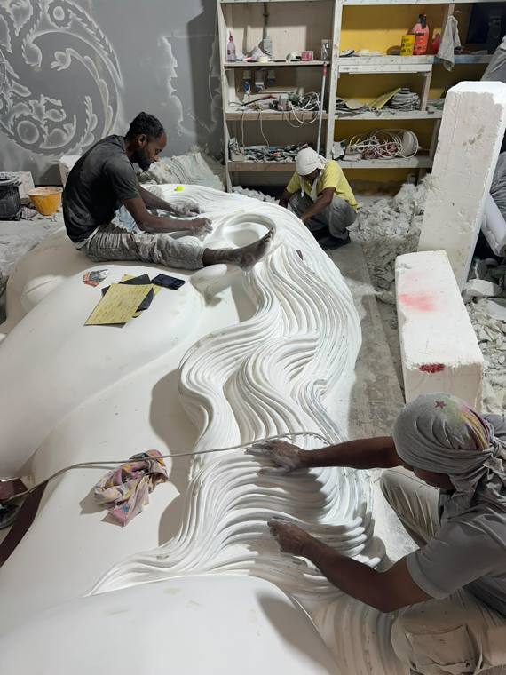 Carving a reclining figure on the workshop floor
