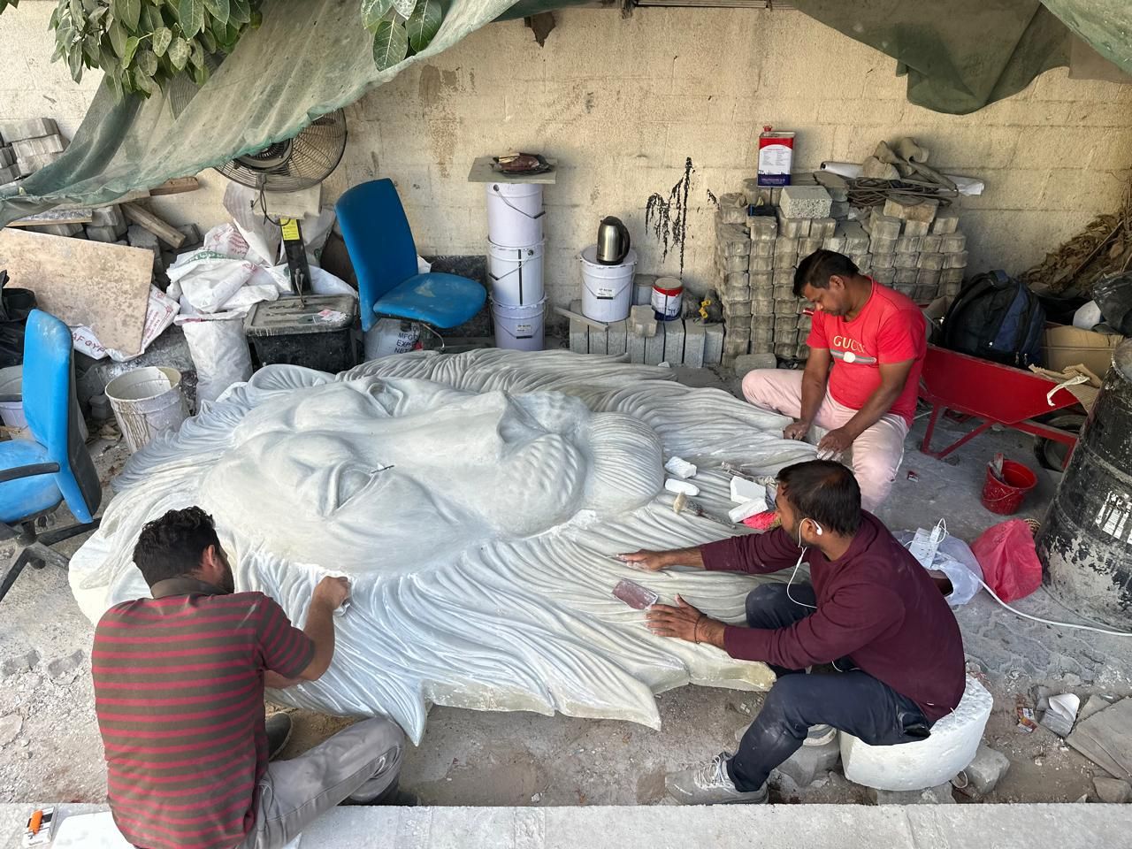 Sculptors carving a large relief on the floor of the Al Quoz workshop