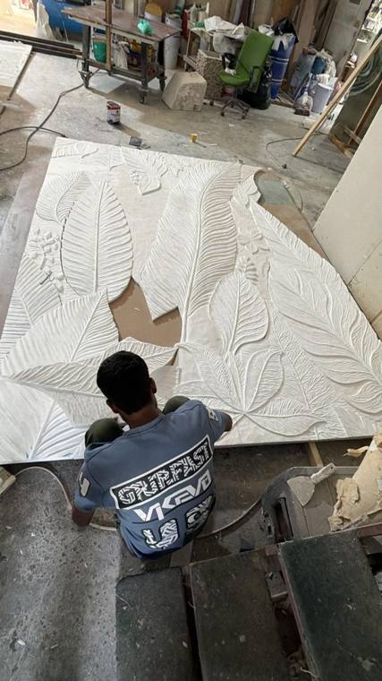 Carving a botanical panel on the workshop floor